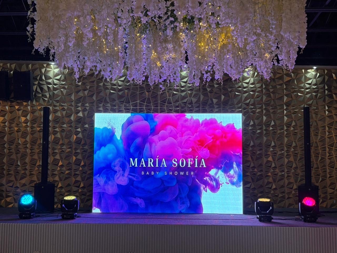 Pantalla LED en un baby shower con techo de flores y cabezas móviles