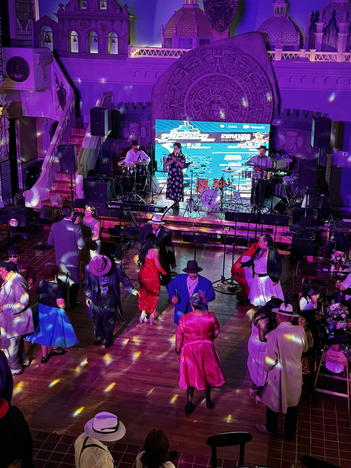 Pista de baile llena con banda en vivo e iluminación morada